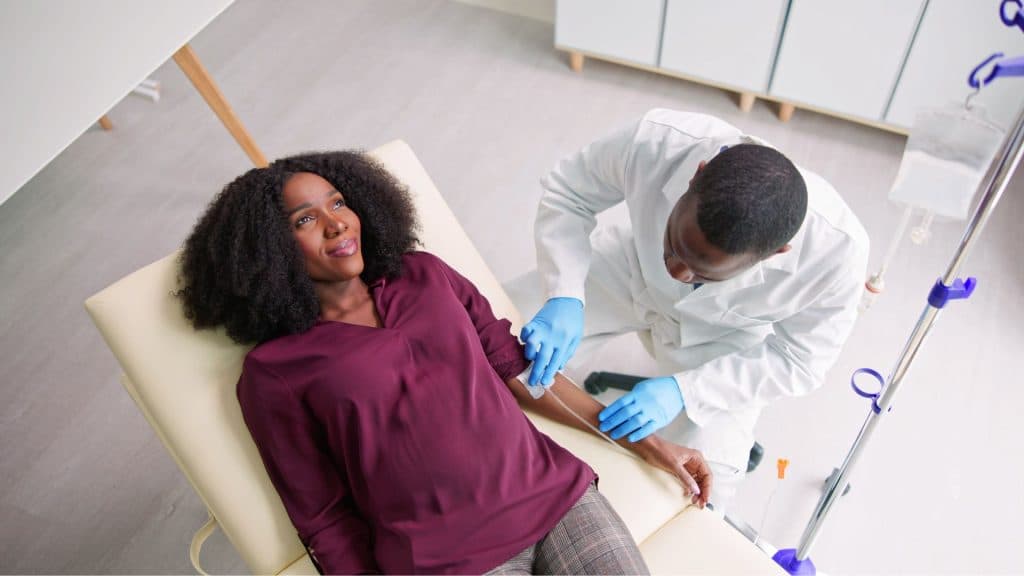 A male medical professional providing a female patient with comfortable, in-home immunoglobulin infusion therapy.