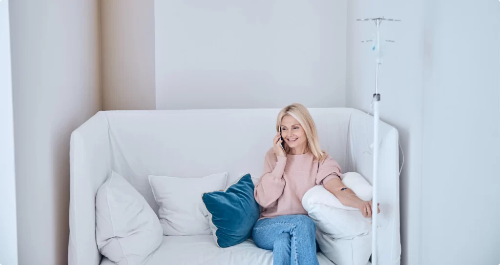 A woman talking on the phone as she sits comfortably while receiving at-home immunoglobulin infusion therapy provided by MedRx.